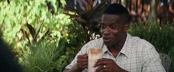 Movie still from “The Binge” (2020), directed by Jeremy Garelick – A man sitting outside with a drink in his hand; Close Up shot, High angle