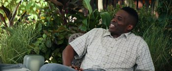 Movie still from “The Binge” (2020), directed by Jeremy Garelick – A man sitting on a chair in a garden; Medium shot, Over the shoulder angle