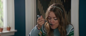 Movie still from “The Binge” (2020), directed by Jeremy Garelick – A woman holding a spoon in her mouth; Close Up shot, High angle