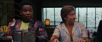 Movie still from “The Binge” (2020), directed by Jeremy Garelick – Two men sitting at a table in front of a window; Medium shot, Over the shoulder angle