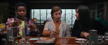 Movie still from “The Binge” (2020), directed by Jeremy Garelick – A man sitting at a table holding a glass of wine; Medium shot, Over the shoulder angle