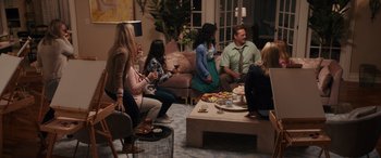 Movie still from “The Binge” (2020), directed by Jeremy Garelick – A group of people sitting around a living room eating and drinking; Wide shot, High angle