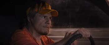 Movie still from “The Binge” (2020), directed by Jeremy Garelick – A man wearing an orange shirt and a yellow hat driving a car; Close Up shot, Low angle