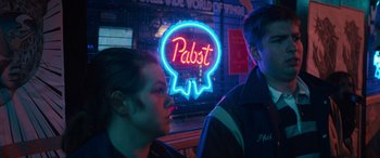 Movie still from “The Binge” (2020), directed by Jeremy Garelick – Two people standing next to each other in front of a neon sign; Close Up shot, Low angle