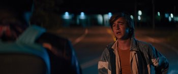 Movie still from “The Binge” (2020), directed by Jeremy Garelick – A young man standing on the side of a road; Close Up shot, Over the shoulder angle