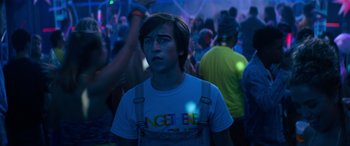 Movie still from “The Binge” (2020), directed by Jeremy Garelick – A young man is standing in front of a crowd of people; Medium shot, Over the shoulder angle