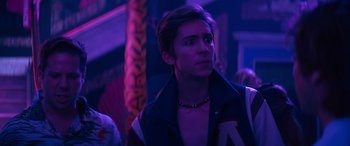 Movie still from “The Binge” (2020), directed by Jeremy Garelick – A young man in a black jacket is looking at the camera; Close Up shot, Over the shoulder angle