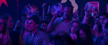 Movie still from “The Binge” (2020), directed by Jeremy Garelick – A group of people sitting in a room with purple lights; Medium shot, Over the shoulder angle