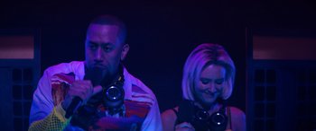 Movie still from “The Binge” (2020), directed by Jeremy Garelick – A man and a woman are standing in front of a camera; Close Up shot, Low angle