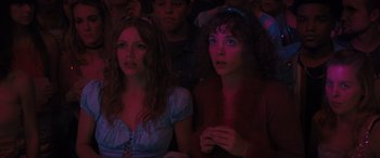 Movie still from “The Binge” (2020), directed by Jeremy Garelick – Two women sitting next to each other in front of a crowd; Medium shot, Low angle