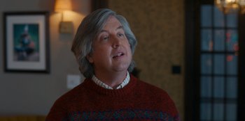 Movie still from “It's A Wonderful Binge” (2022), directed by Jordan VanDina – A man with grey hair wearing a red sweater; Close Up shot, Over the shoulder angle