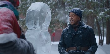 Movie still from “It's A Wonderful Binge” (2022), directed by Jordan VanDina – A man standing in front of an ice sculpture; Medium shot, Over the shoulder angle