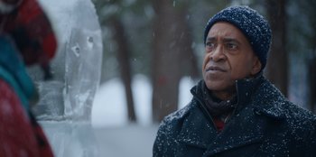Movie still from “It's A Wonderful Binge” (2022), directed by Jordan VanDina – A man standing in the snow near an ice sculpture; Close Up shot, Over the shoulder angle
