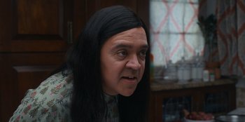 Movie still from “It's A Wonderful Binge” (2022), directed by Jordan VanDina – A man with long black hair and a black wig; Close Up shot, Over the shoulder angle