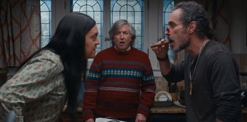 Movie still from “It's A Wonderful Binge” (2022), directed by Jordan VanDina – Three people are standing in front of each other in a kitchen; Medium shot, Over the shoulder angle