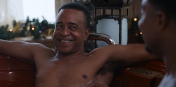 Movie still from “It's A Wonderful Binge” (2022), directed by Jordan VanDina – A man sitting in a chair with his arms behind his head; Close Up shot, Low angle
