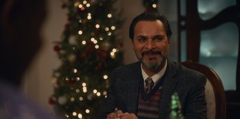 Movie still from “It's A Wonderful Binge” (2022), directed by Jordan VanDina – A man sitting in front of a christmas tree; Close Up shot, Over the shoulder angle