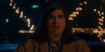 Movie still from “It's A Wonderful Binge” (2022), directed by Jordan VanDina – A man with long black hair is staring at the camera; Close Up shot, Low angle