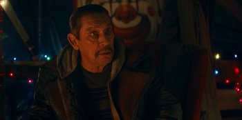 Movie still from “It's A Wonderful Binge” (2022), directed by Jordan VanDina – An older man sitting in front of an angry face; Close Up shot, Over the shoulder angle