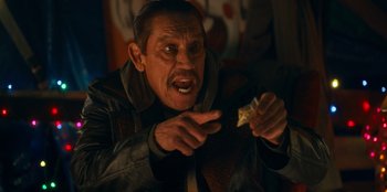 Movie still from “It's A Wonderful Binge” (2022), directed by Jordan VanDina – An older man holding a piece of food in his hand; Close Up shot, High angle