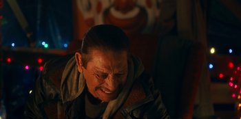 Movie still from “It's A Wonderful Binge” (2022), directed by Jordan VanDina – An older man is smiling while sitting in a chair; Close Up shot, Over the shoulder angle