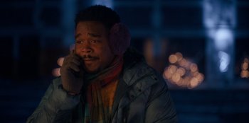 Movie still from “It's A Wonderful Binge” (2022), directed by Jordan VanDina – A man wearing a jacket and ear muffs while talking on a cell phone; Close Up shot, Over the shoulder angle
