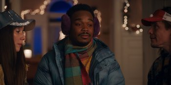 Movie still from “It's A Wonderful Binge” (2022), directed by Jordan VanDina – A man wearing ear warmers and a jacket; Medium shot, Over the shoulder angle