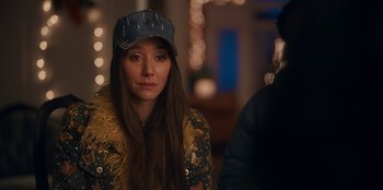 Movie still from “It's A Wonderful Binge” (2022), directed by Jordan VanDina – A woman wearing a denim hat and a jacket; Close Up shot, Over the shoulder angle