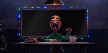 Movie still from “It's A Wonderful Binge” (2022), directed by Jordan VanDina – A man sitting at a table with a glass of milk; Medium shot, Low angle