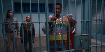 Movie still from “It's A Wonderful Binge” (2022), directed by Jordan VanDina – A man in a jail cell holding a cell phone; Medium shot, High angle