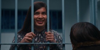 Movie still from “It's A Wonderful Binge” (2022), directed by Jordan VanDina – A man with a painted face behind a metal fence; Medium shot, Over the shoulder angle