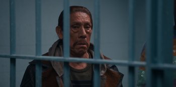 Movie still from “It's A Wonderful Binge” (2022), directed by Jordan VanDina – An old man in a jail cell looking at the camera; Close Up shot, Over the shoulder angle