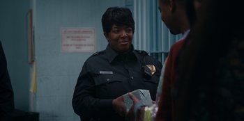 Movie still from “It's A Wonderful Binge” (2022), directed by Jordan VanDina – A police officer is handing out presents to a man; Close Up shot, Over the shoulder angle