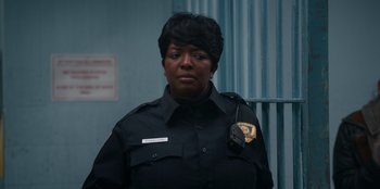Movie still from “It's A Wonderful Binge” (2022), directed by Jordan VanDina – A woman in a police uniform is looking at the camera; Close Up shot, Over the shoulder angle