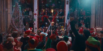 Movie still from “It's A Wonderful Binge” (2022), directed by Jordan VanDina – A group of people sitting in a room with christmas decorations on the wall; Extreme Wide shot, High angle