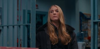 Movie still from “It's A Wonderful Binge” (2022), directed by Jordan VanDina – A woman with long blonde hair wearing a black jacket; Close Up shot, Over the shoulder angle