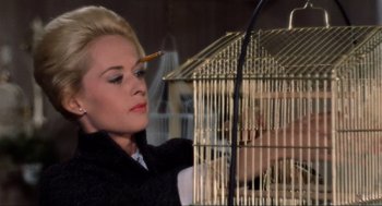Movie still from “The Birds” (1963), directed by Alfred Hitchcock – A woman holding a bird in a cage; Close Up shot, Low angle
