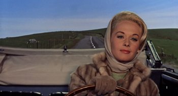 Movie still from “The Birds” (1963), directed by Alfred Hitchcock – A woman driving a car on a road; Close Up shot, Low angle
