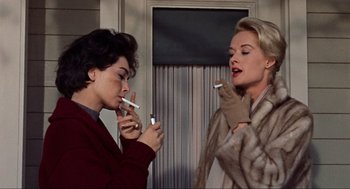 Movie still from “The Birds” (1963), directed by Alfred Hitchcock – Two women are smoking cigarettes in front of each other; Close Up shot, Low angle