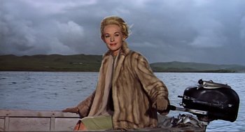 Movie still from “The Birds” (1963), directed by Alfred Hitchcock – A woman sitting on the back of a boat in the water; Medium shot, Low angle