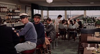 Movie still from “The Birds” (1963), directed by Alfred Hitchcock – A group of people sitting at tables in a restaurant; Wide shot, Over the shoulder angle