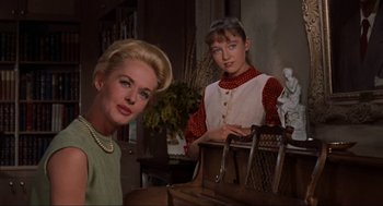 Movie still from “The Birds” (1963), directed by Alfred Hitchcock – A woman sitting next to a young girl in front of a piano; Medium shot, Low angle