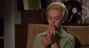 Movie still from “The Birds” (1963), directed by Alfred Hitchcock – A woman sitting in a chair with a cigarette in her mouth; Close Up shot, High angle