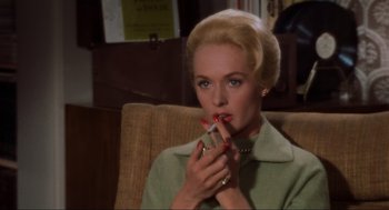 Movie still from “The Birds” (1963), directed by Alfred Hitchcock – A woman sitting in a chair with a cigarette in her mouth; Close Up shot, High angle