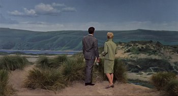 Movie still from “The Birds” (1963), directed by Alfred Hitchcock – A painting of a man and a woman standing on a hill; Extreme Wide shot, Low angle