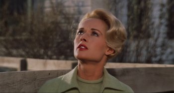 Movie still from “The Birds” (1963), directed by Alfred Hitchcock – A woman in a green jacket looking up at the sky; Close Up shot, Low angle