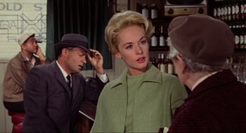 Movie still from “The Birds” (1963), directed by Alfred Hitchcock – A woman in a green coat and a man in a suit; Medium shot, Over the shoulder angle