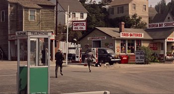 Movie still from “The Birds” (1963), directed by Alfred Hitchcock – Two men are walking down the street in front of a gas station; Extreme Wide shot, High angle