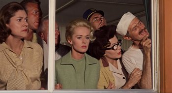 Movie still from “The Birds” (1963), directed by Alfred Hitchcock – A group of people looking out of a window; Medium shot, Low angle