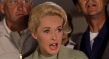 Movie still from “The Birds” (1963), directed by Alfred Hitchcock – A woman with blonde hair and blue eye shadow; Close Up shot, Low angle